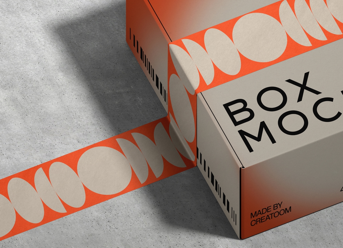 Cardboard box with "BOX MOCK" text, wrapped in orange tape with cream ovals on a concrete surface. Modern and sleek design with a creative vibe.