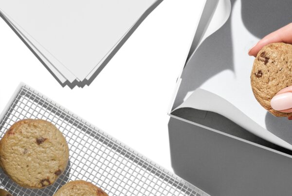 A collection of white and kraft bakery packaging items, including a square cake box and a paper bag, arranged on a neutral surface.