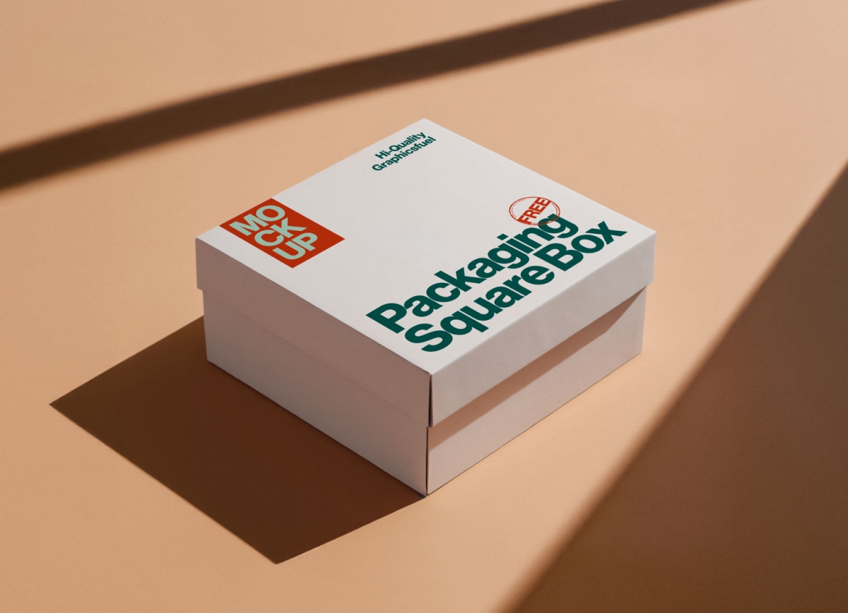 A white square packaging box with a lid, featuring green and orange branding, sitting on a tan surface with sharp shadows.