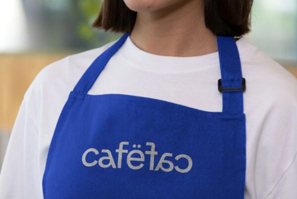 A close-up of a person wearing a vibrant blue fabric apron over a white t-shirt.