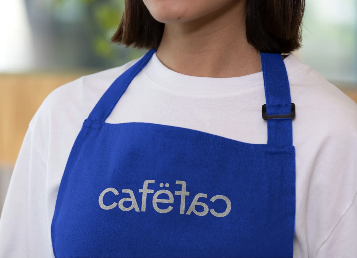 A close-up of a person wearing a vibrant blue fabric apron over a white t-shirt.