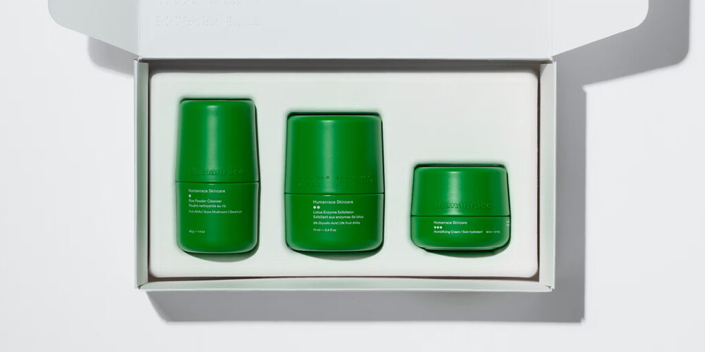 Three vibrant green Humanrace skincare containers neatly arranged inside a minimalist white cardboard box.