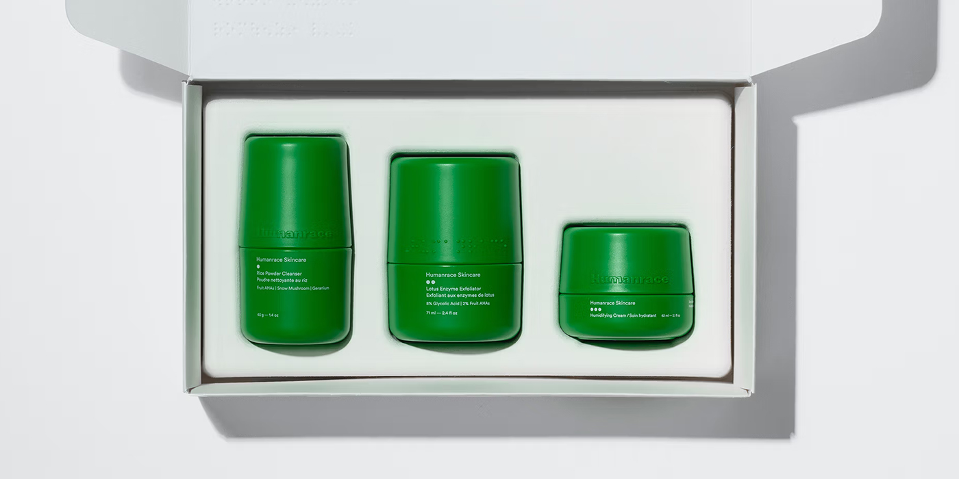 Three vibrant green Humanrace skincare containers neatly arranged inside a minimalist white cardboard box.