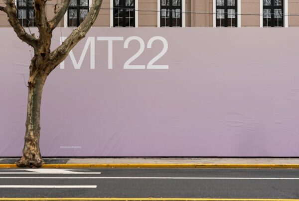 A large lavender construction hoarding banner on a city street next to a tree and asphalt road.
