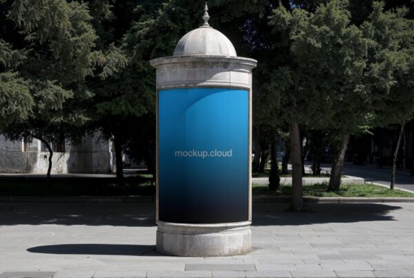 A vertical blue-to-black gradient advertisement displayed on a vintage stone poster column surrounded by green trees along a paved city street.