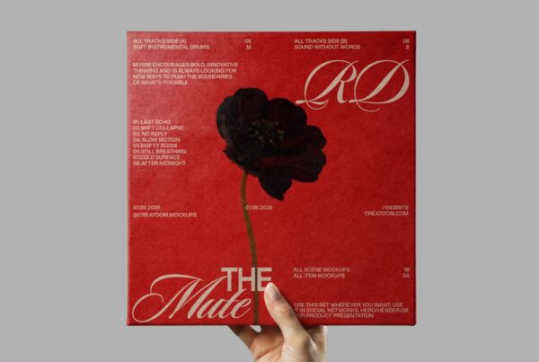 A hand holds a vibrant red textured vinyl record cover featuring a central dark flower and elegant typography against a solid gray background.