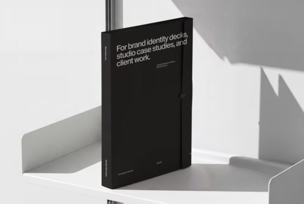 A black presentation folder with white typography standing upright on a minimalist white metal rail shelf.