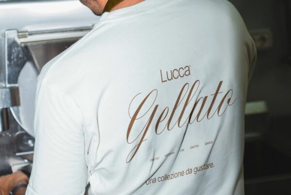 Back view of a person wearing a white t-shirt with a custom gelato brand design, working in an artisanal setting.