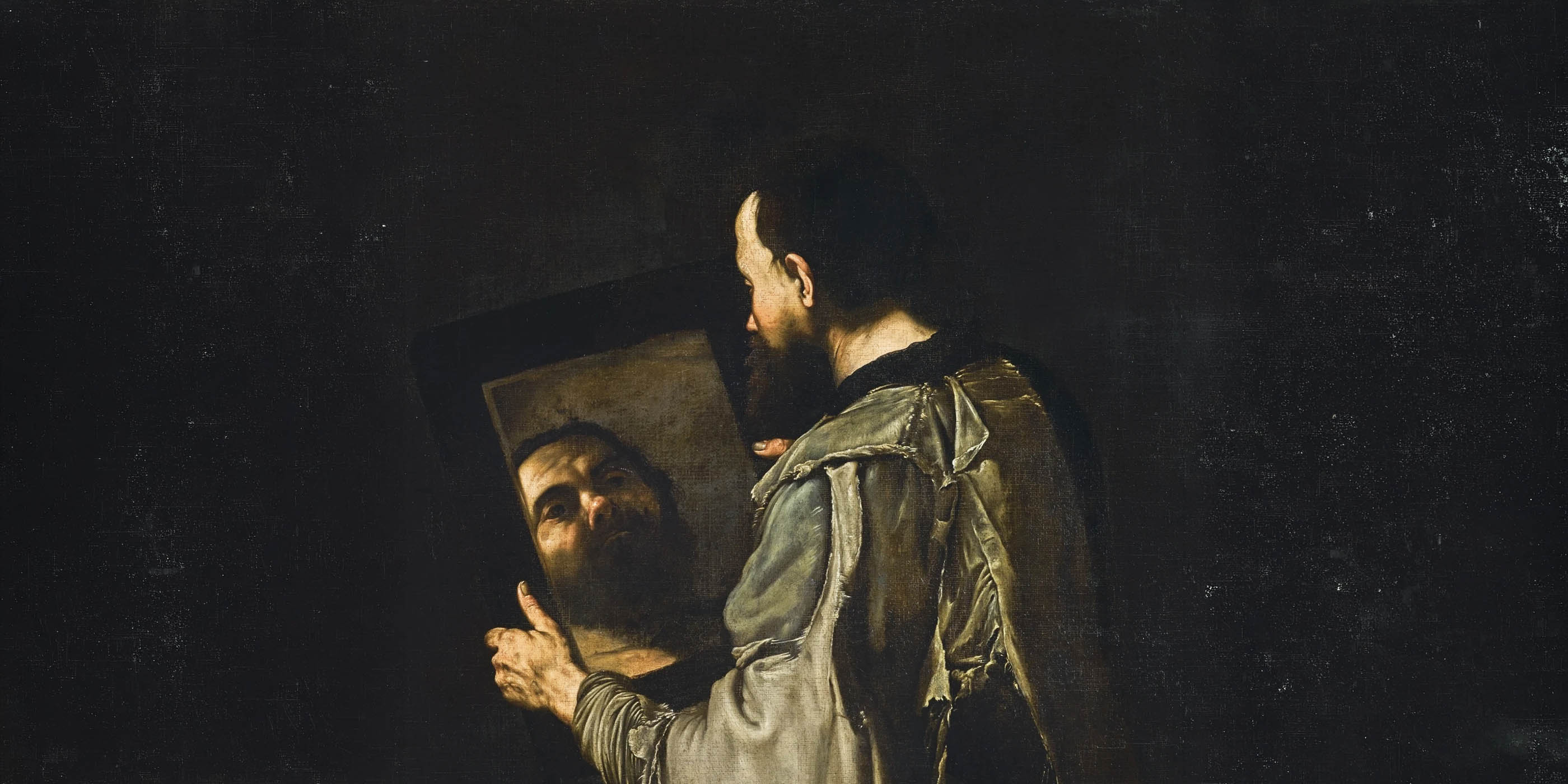 A dramatic Baroque oil painting by Jusepe de Ribera titled "A Philosopher Holding a Mirror," featuring a bearded man in profile against a stark, black background. The man has short dark hair and wears a tattered, light gray tunic. He holds up a large, dark-framed mirror in his hands, gazing intently into it. The mirror reflects a clear, brightly illuminated view of his own weathered face and full beard, creating a strong contrast between the dimly lit surroundings and the bright reflection.